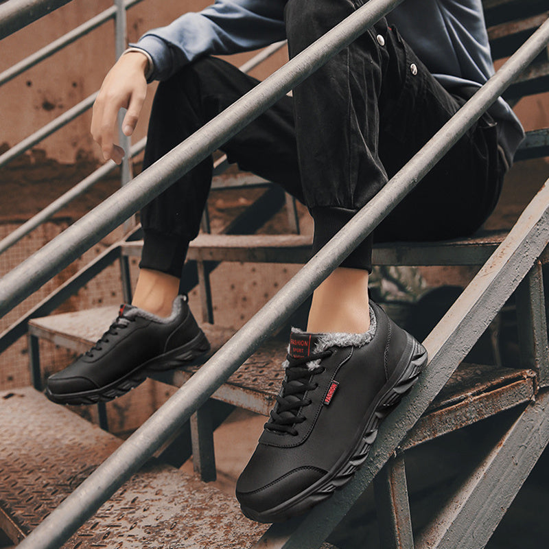 Men's black winter sneakers on stairs, plush lining, lace-up front and tread sole.