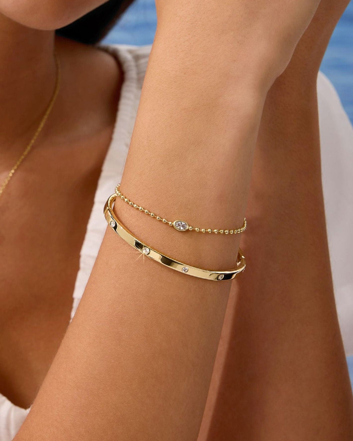 Gold-tone bangle bracelet with small round diamond stations, worn on wrist