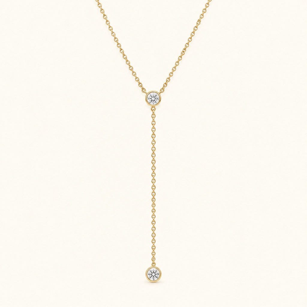 Gold-tone lariat necklace with round diamond bezel stones and dangling charm