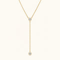 Gold-tone lariat necklace with round diamond bezel stones and dangling charm