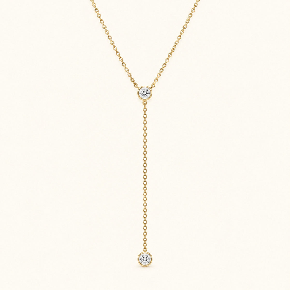Gold-tone lariat necklace with round diamond bezel stones and dangling charm