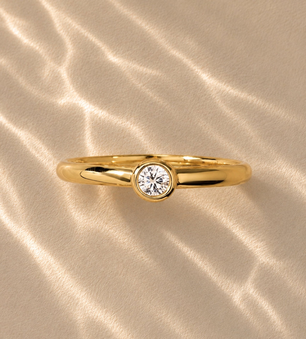 Gold-tone band with bezel-set round stone, close-up