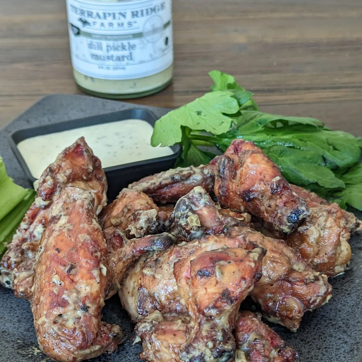 Jar of dill pickle mustard in background with grilled chicken pieces