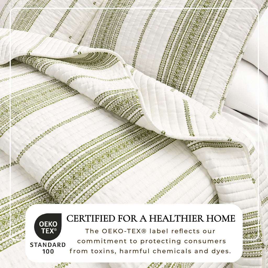 Striped quilt close-up with cream base and green vertical bands, quilted channels detail.