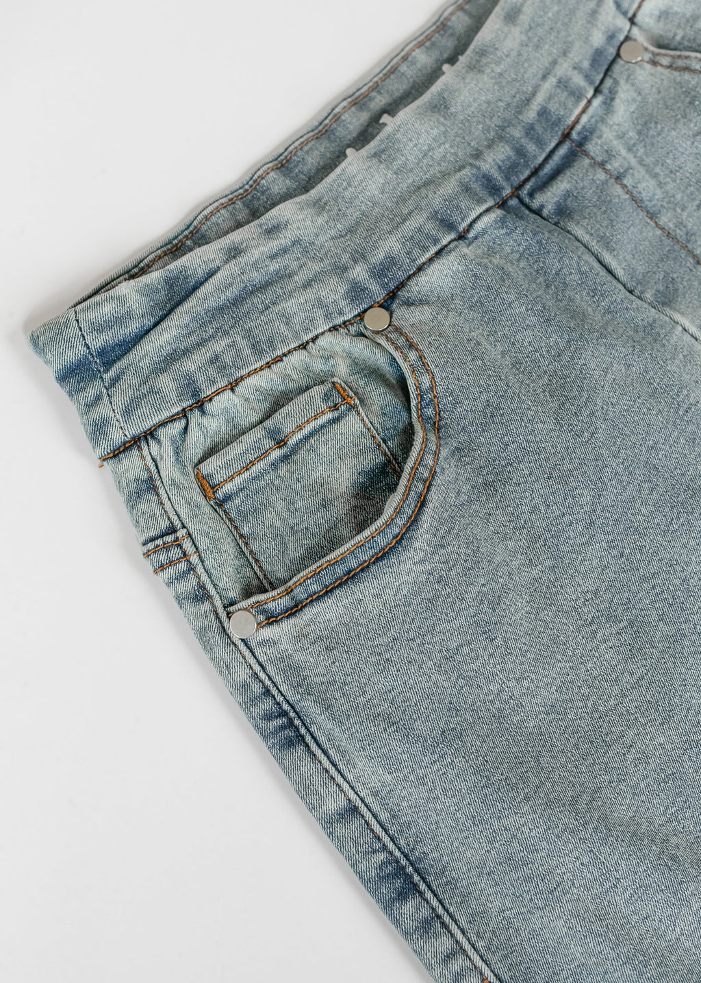 Light wash denim skirt close-up of stitched pocket with contrast orange thread