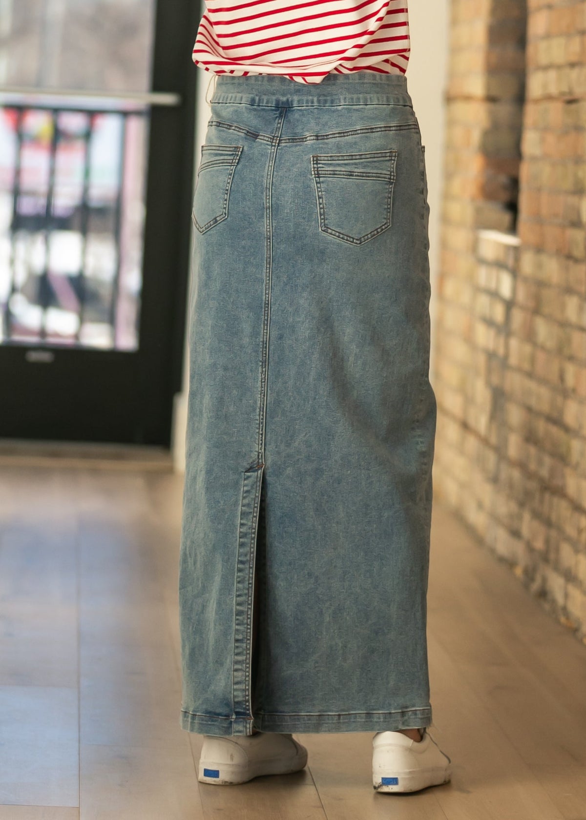 Back view of light-wash denim maxi skirt with two patch pockets and slit