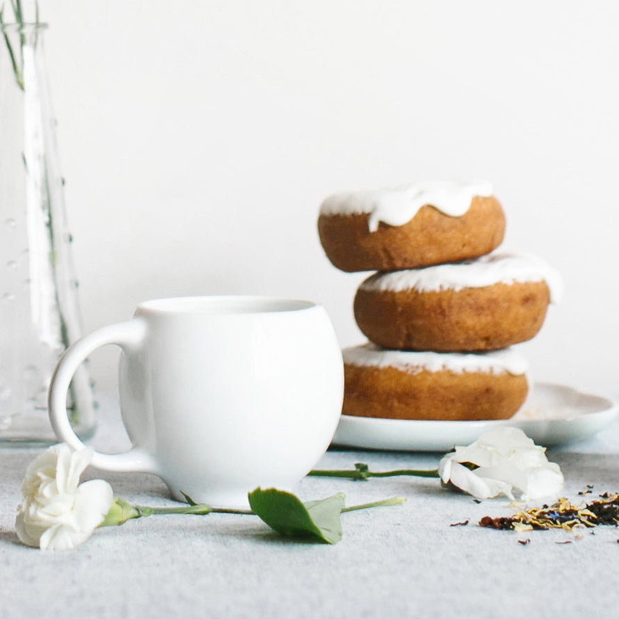 White ceramic teacup with curved handle on a matching saucer