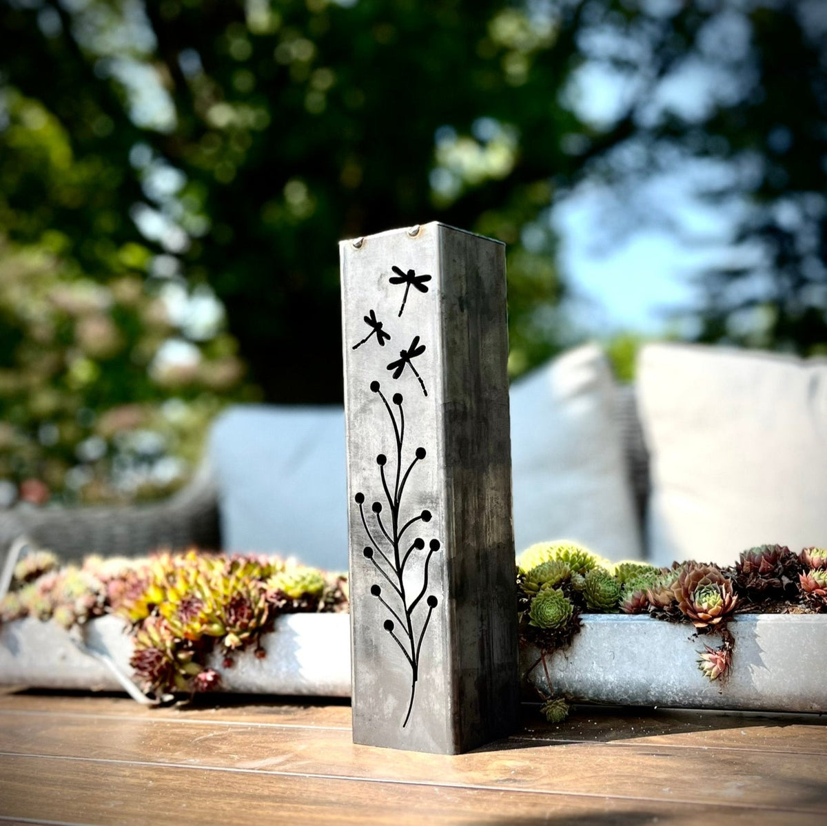 Steel solar luminary pillar with black branch, flowers, and dragonfly silhouette