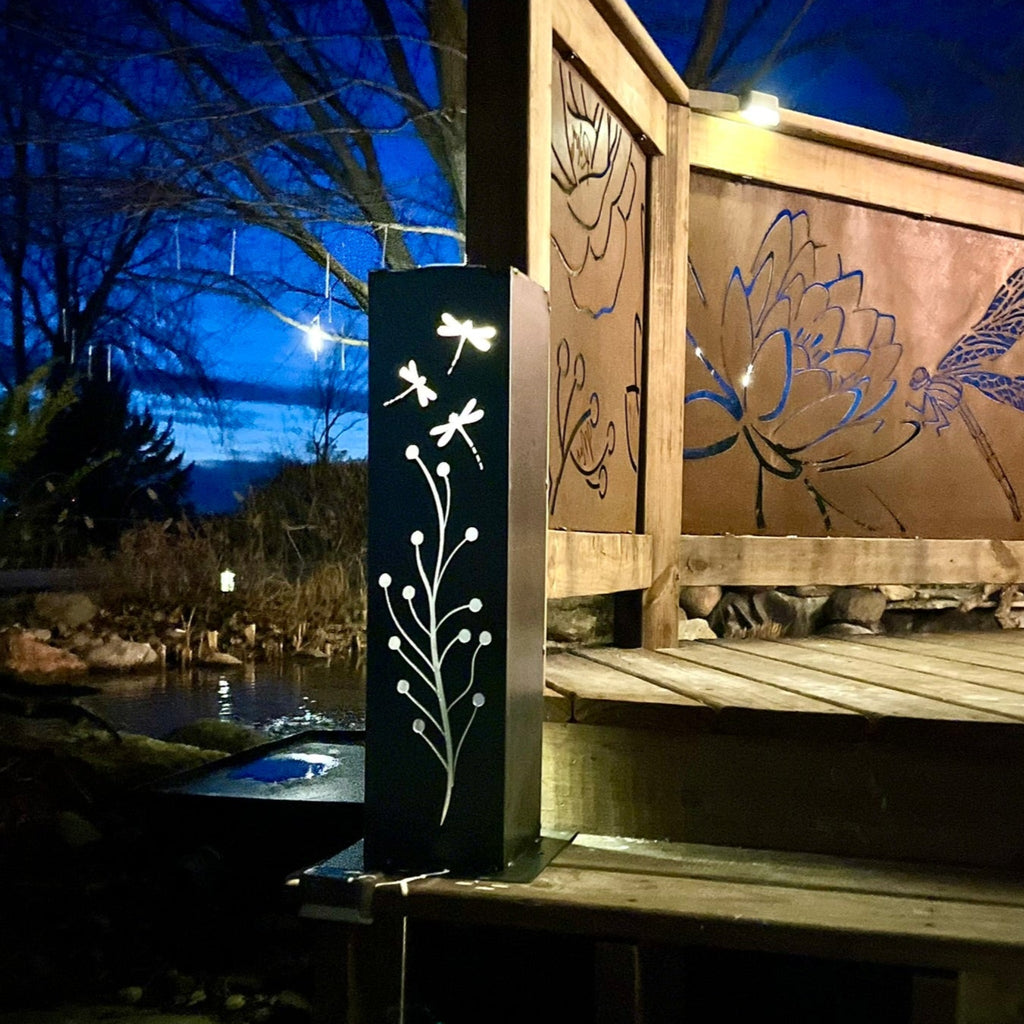 Steel solar luminary pillar with glowing etched branch and dragonfly motif