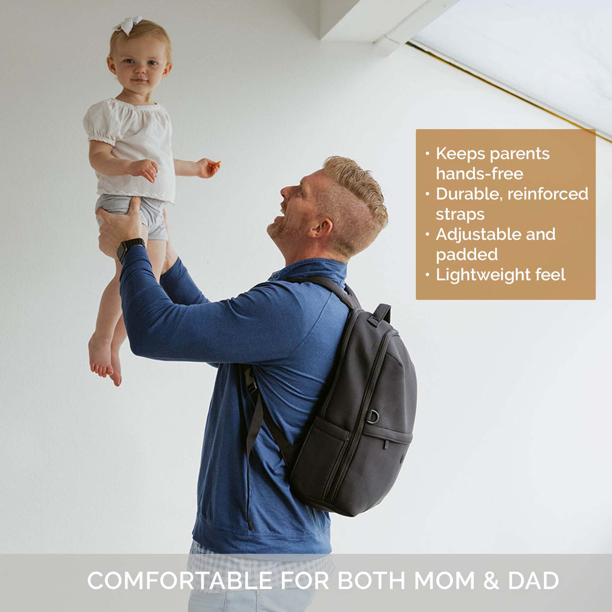 Black diaper backpack worn by parent carrying a child indoors