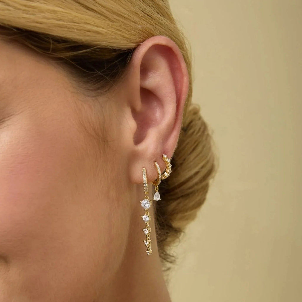 Gold-tone CZ hoop earrings with small pear-shaped dangling charms at ear