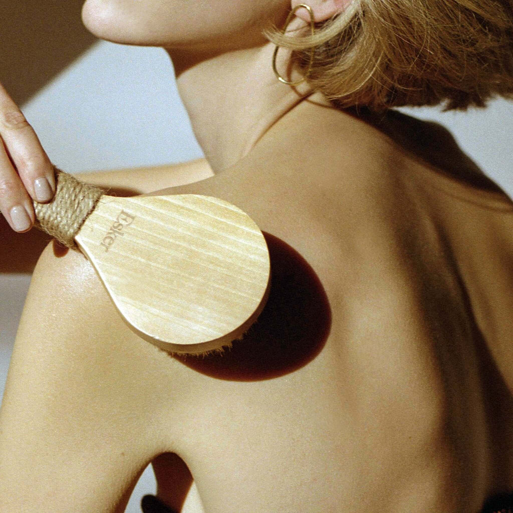 Wooden-backed dry brush with natural bristles pressed to upper arm