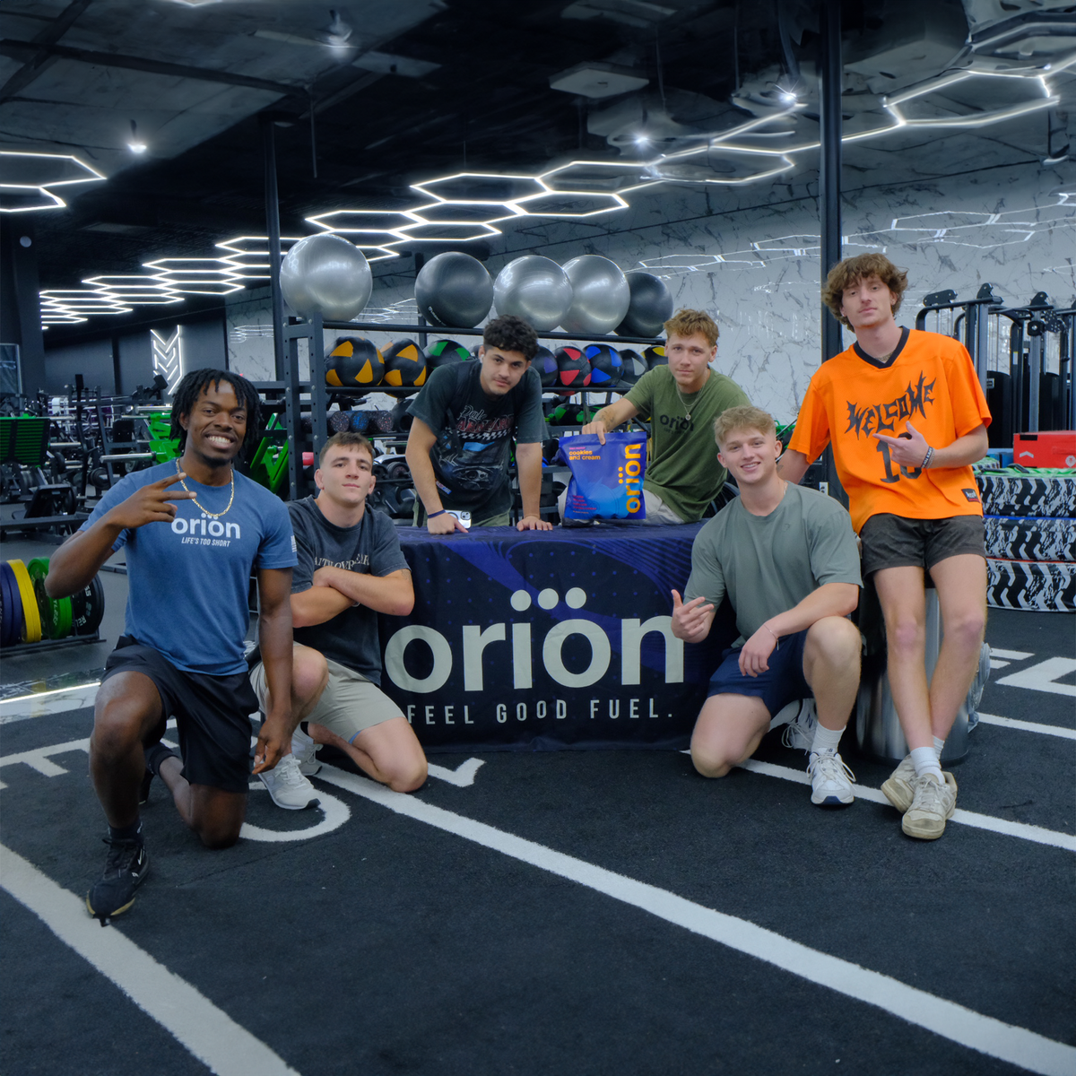 People posing with Orion protein tub in a gym