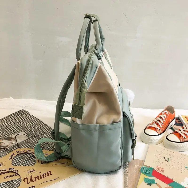 Light blue and green patchwork backpack with double handle and front zip pocket.