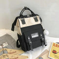 Black and cream backpack with front patch pocket and pom-pom charm