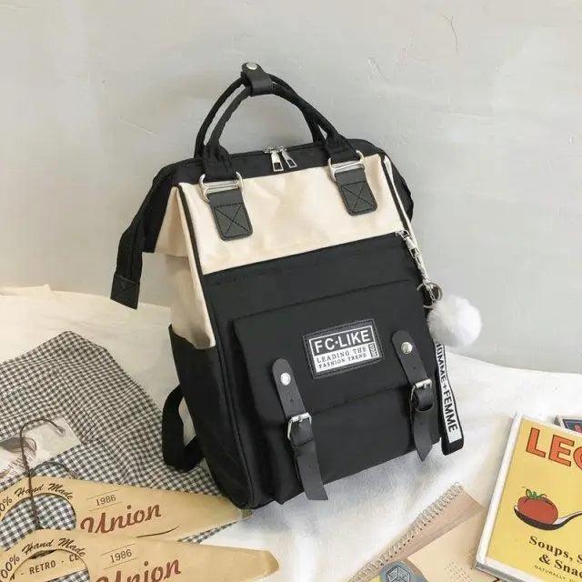 Black and cream backpack with front patch pocket and pom-pom charm