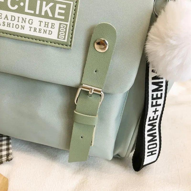 Mint green backpack front label and dangling tag with pom-pom detail.