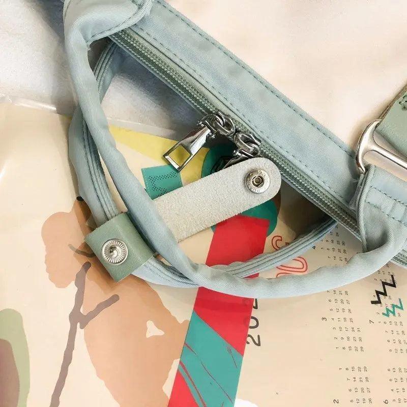 Light blue backpack close-up showing zip pocket and adjustable shoulder strap.