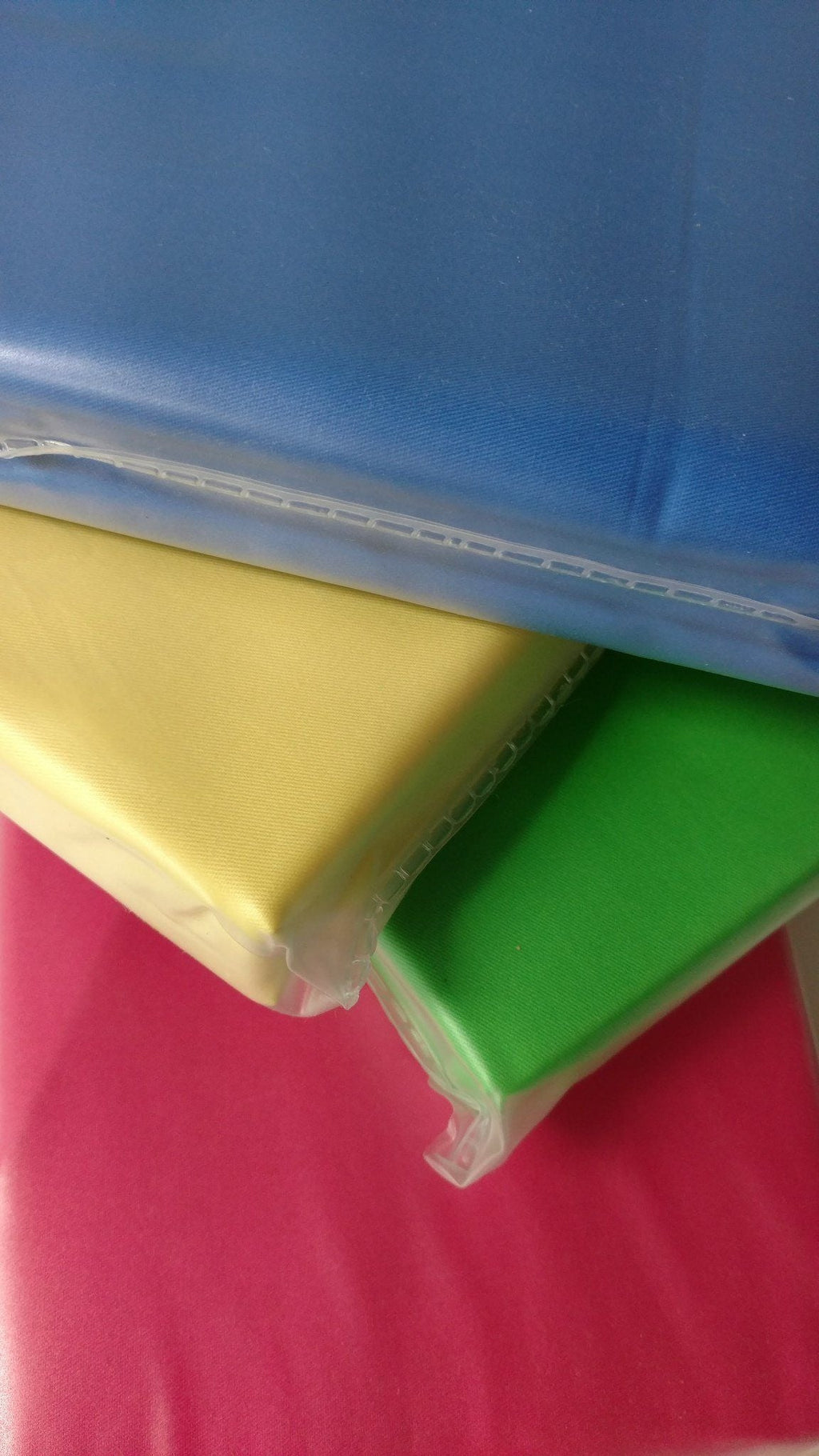 Banana yellow cotton duvet corner peeking from clear packaging over stacked colors