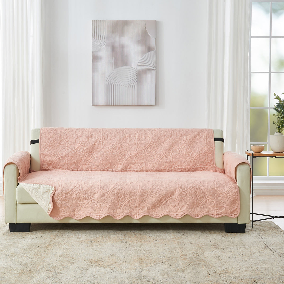 Quilted sofa protector in blush pink with raised medallion pattern across seat and back