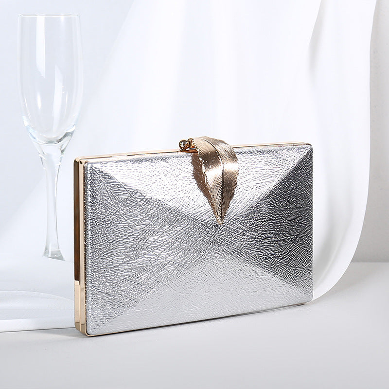 Silver textured small evening crossbody bag with gold-tone bow clasp.