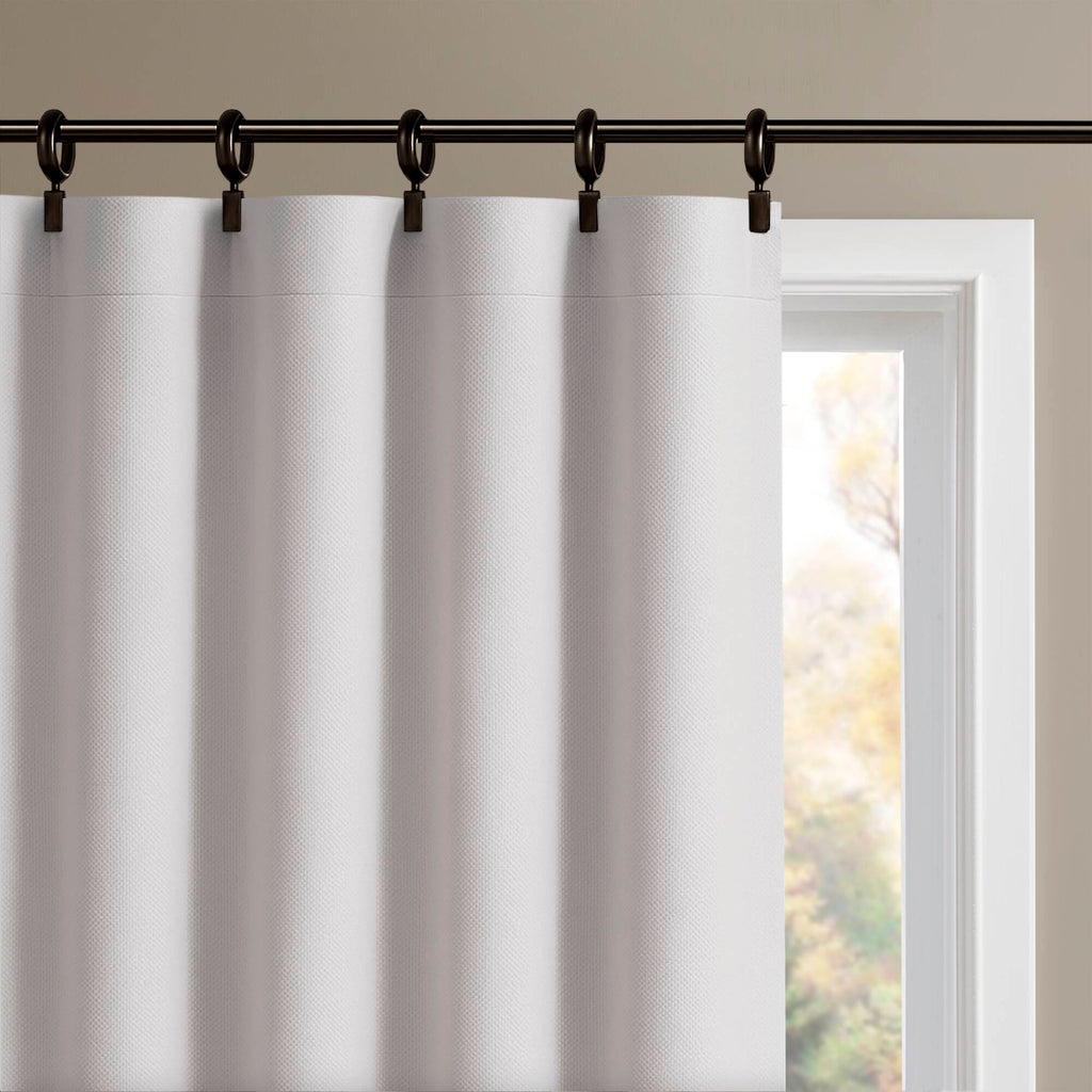 White blackout curtain panels hanging from a rod with evenly spaced rings