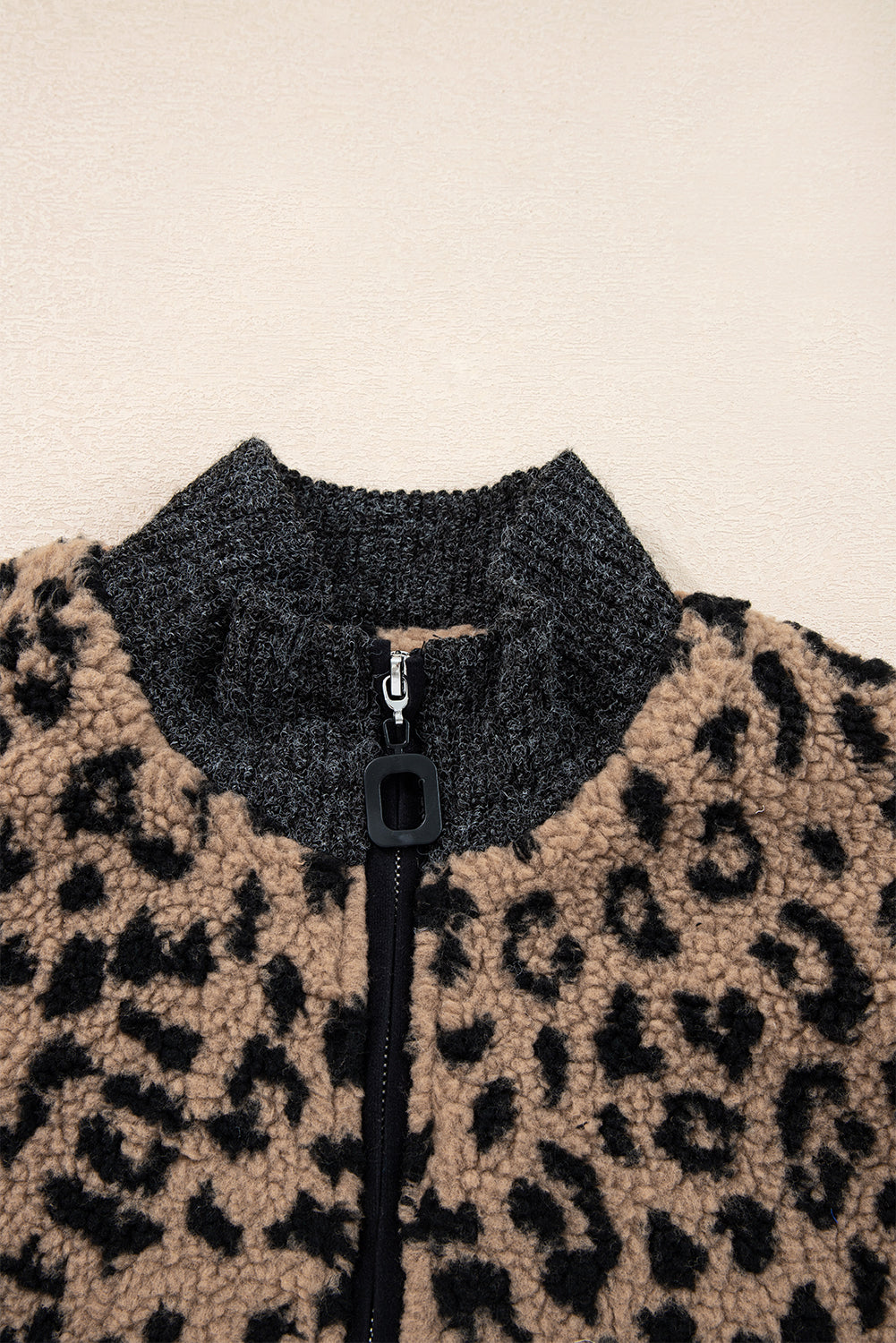 Leopard-print fleece jacket close-up of stand collar and front zipper with black trim.