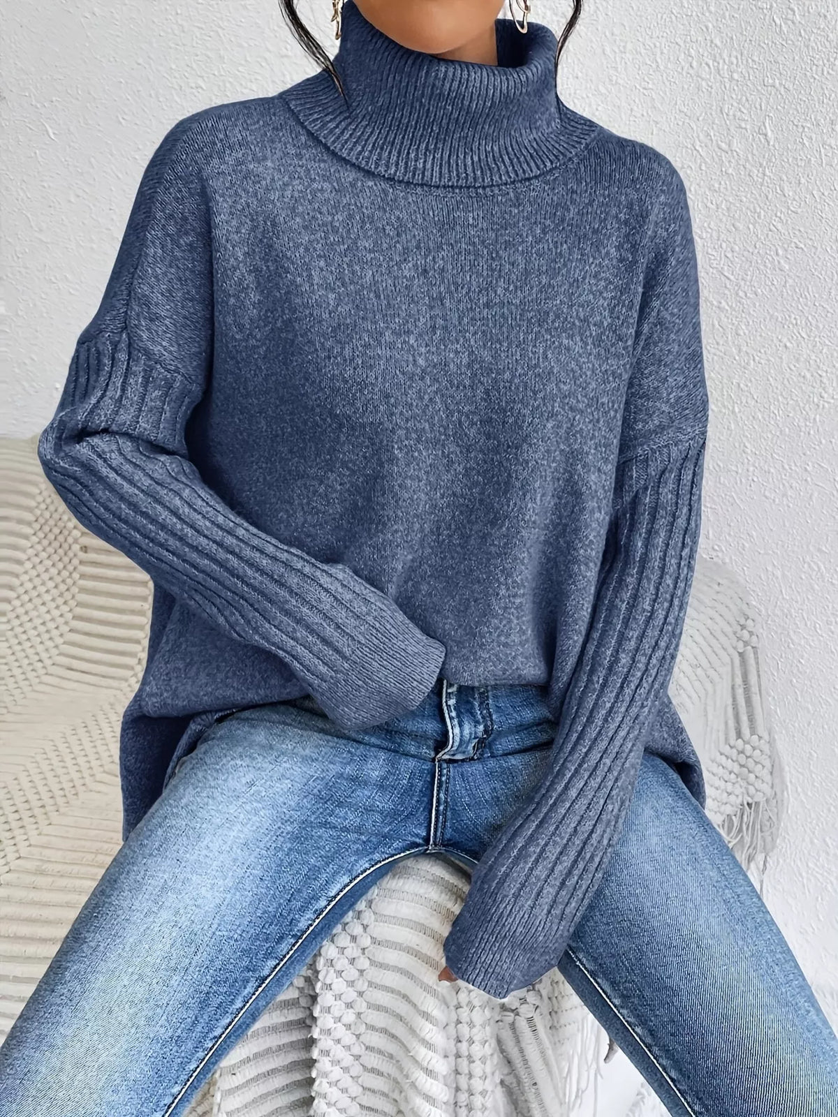 Navy turtleneck knit sweater with ribbed cuffs and high-low hem over blue jeans