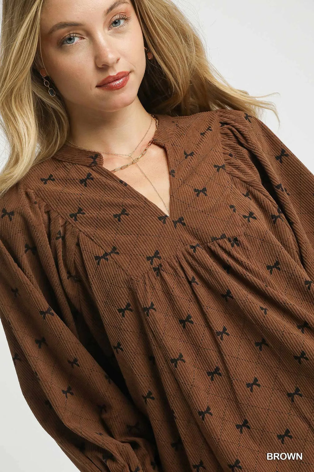 Brown corduroy bow-print blouse close-up with V-neck and textured fabric