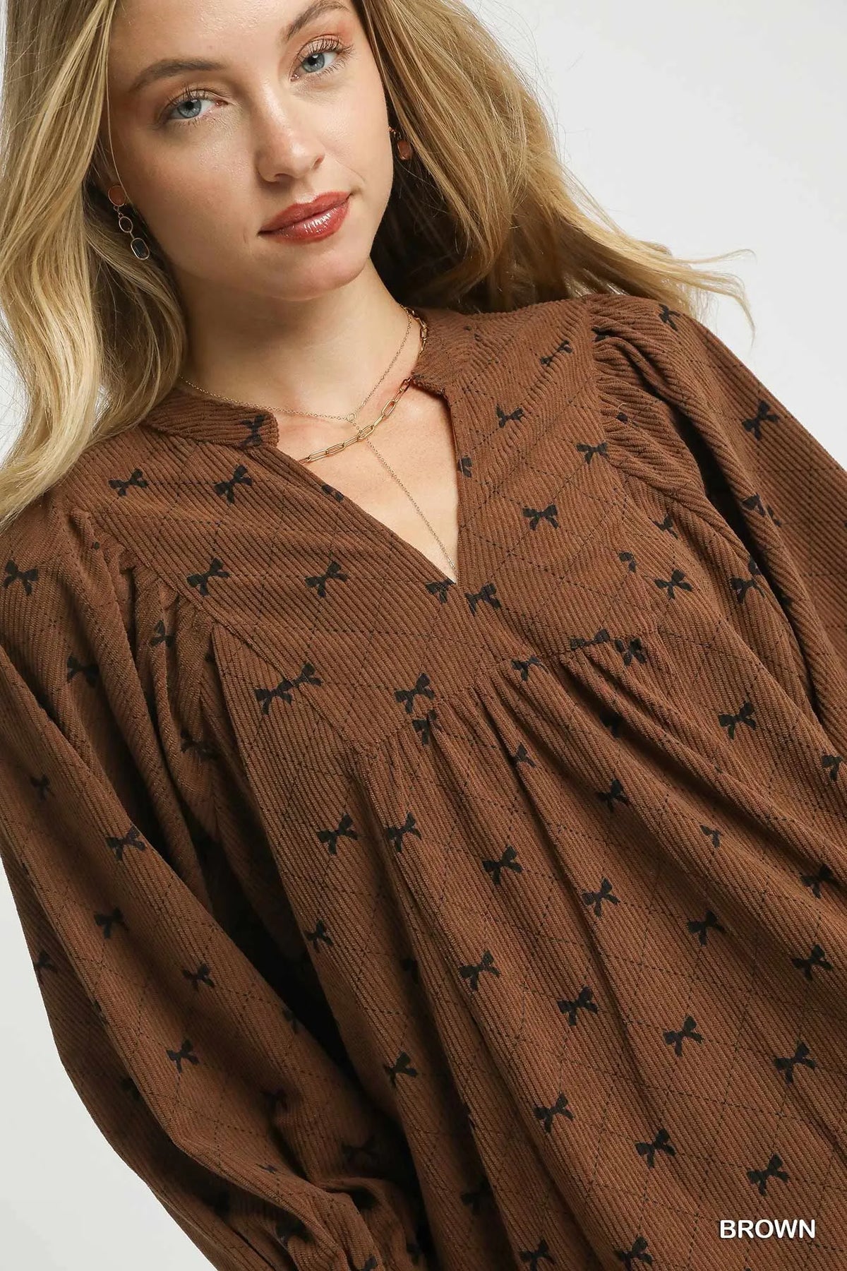 Brown corduroy bow-print blouse close-up with V-neck and textured fabric