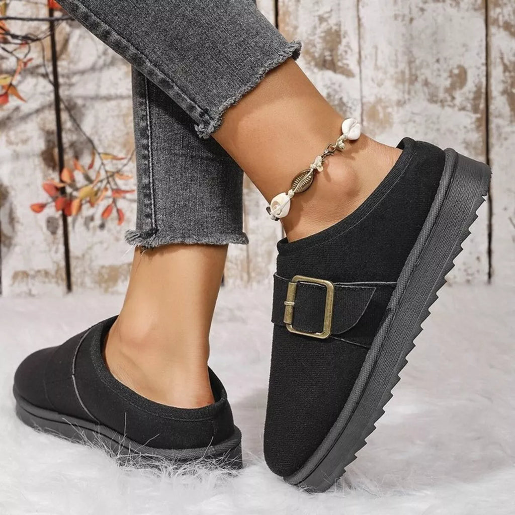 Black plush-lined slippers, side view, with front buckle strap and thick sole