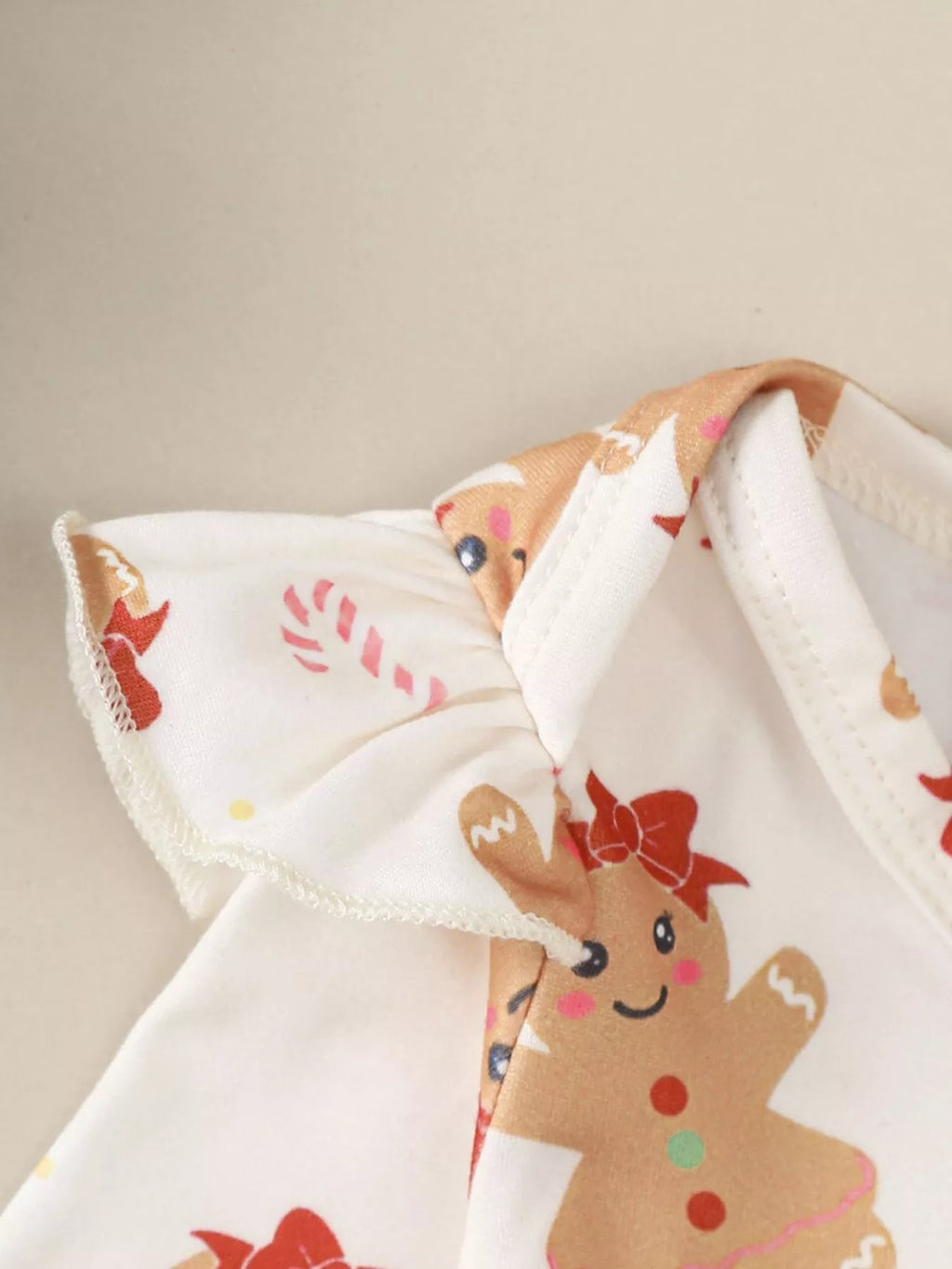 White long-sleeve bodysuit with gingerbread character print and soft neckline trim