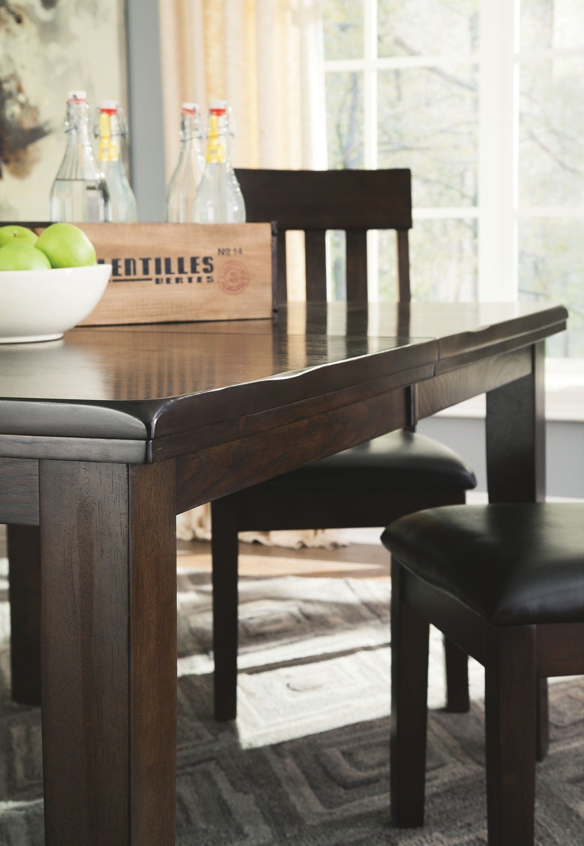 Close view of dark brown dining table with black upholstered bench and chair seats