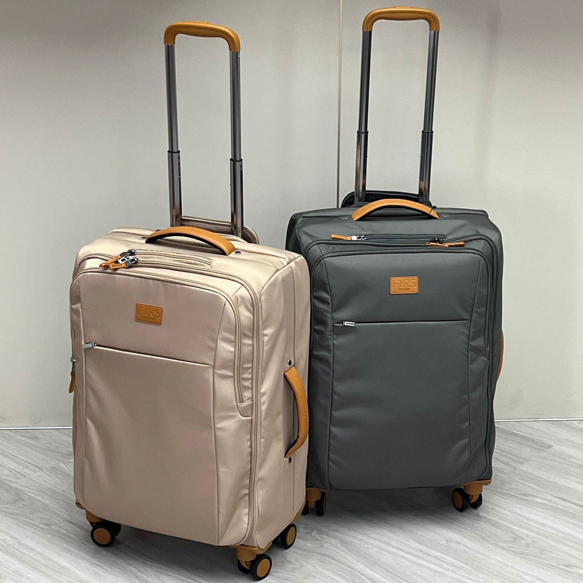 Pair of ultra-light wheeled trolley suitcases, cream and dark gray, with telescoping handles