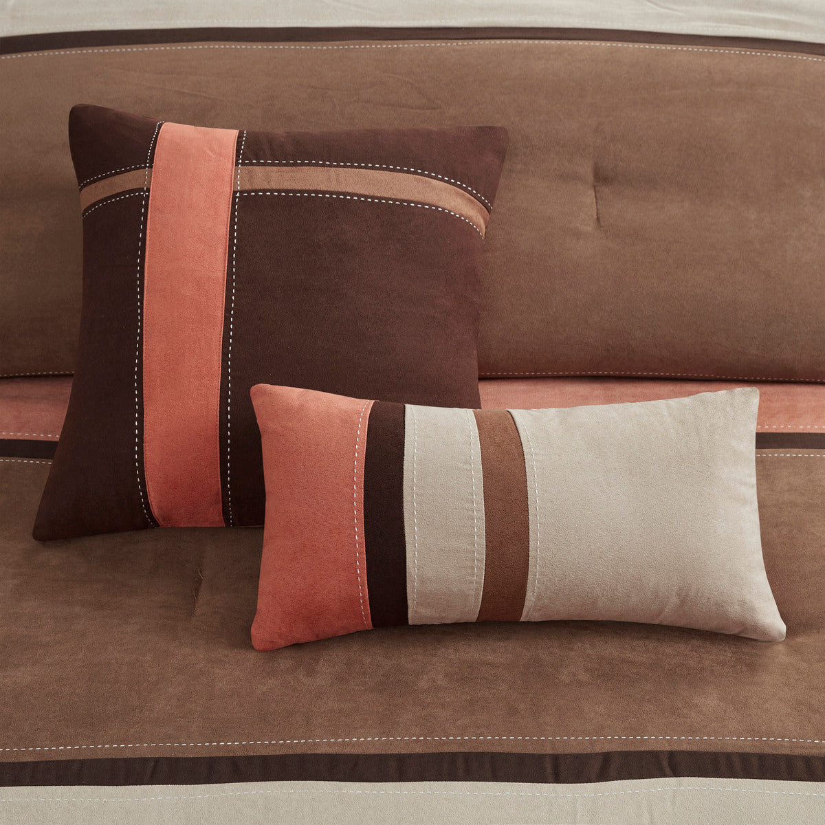 Faux suede accent pillows in coral, brown, and cream with contrast striped bands