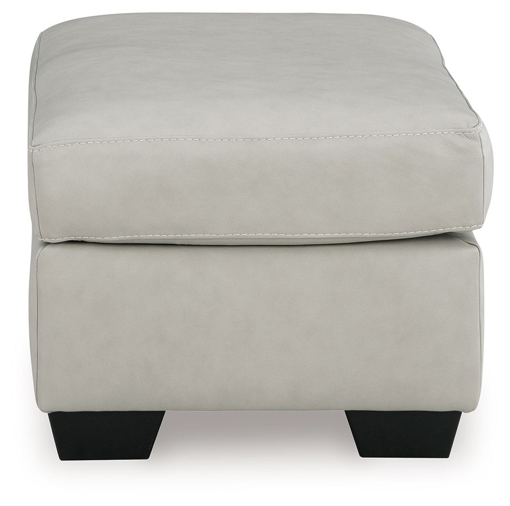 Light gray upholstered ottoman with stitched top seam and black square legs