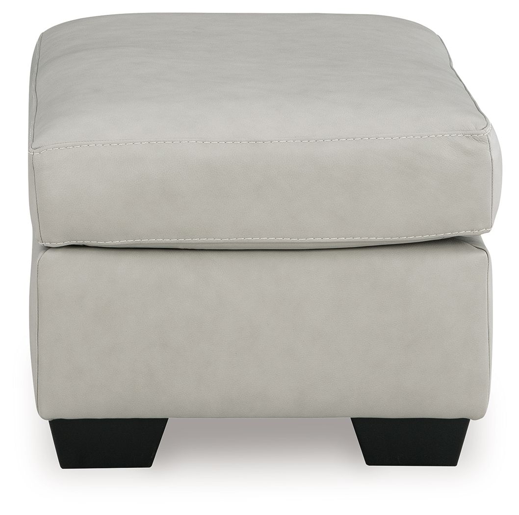 Light gray upholstered ottoman with stitched top seam and black square legs