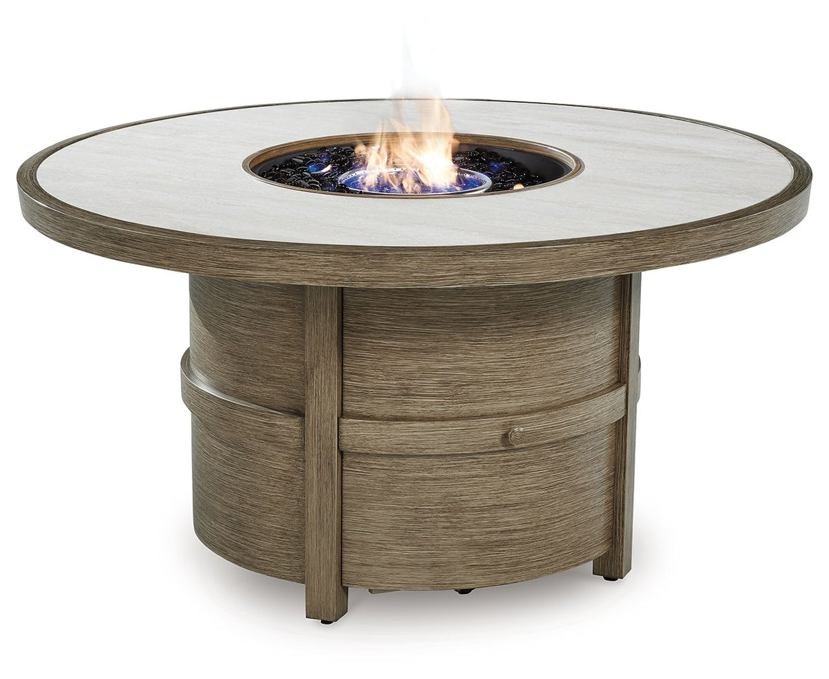 Round fire pit table with beige top and lit burner bowl, set in wood pedestal