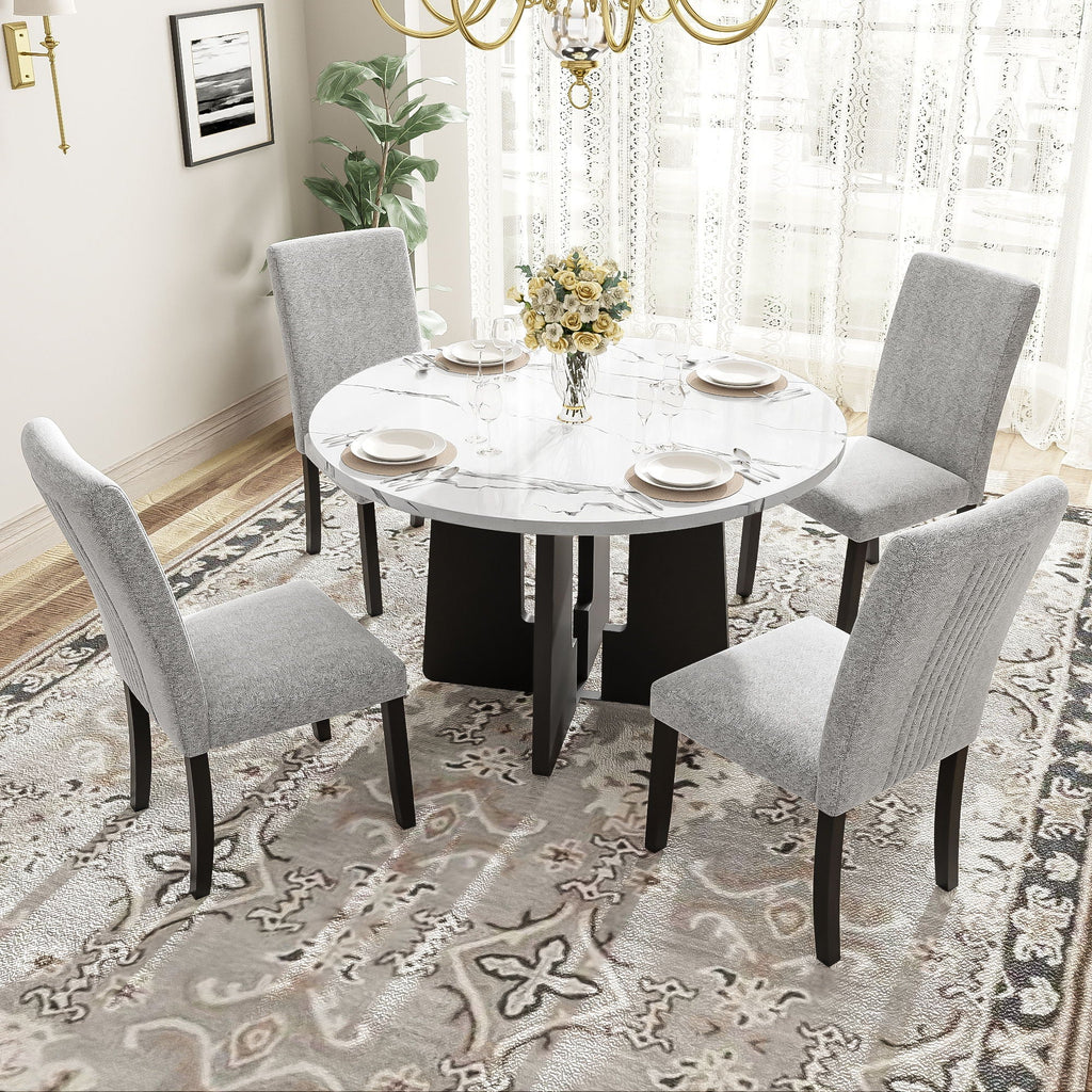 Round white dining table with four gray upholstered chairs around it, black legs