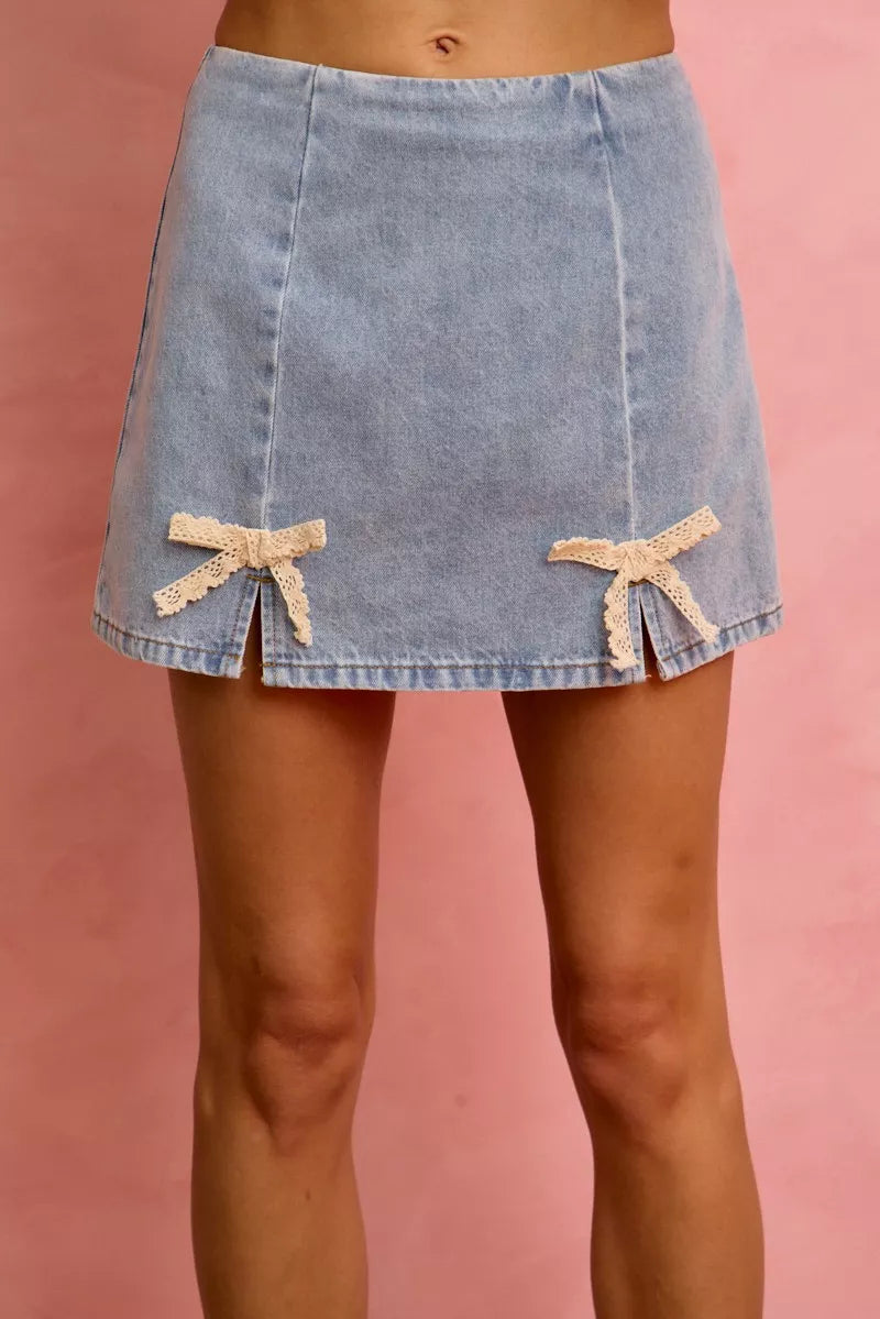 Light-wash denim mini skirt with lace ribbon bow details at sides
