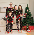 Family Christmas pajama set worn by four people, dark print with red cuffs