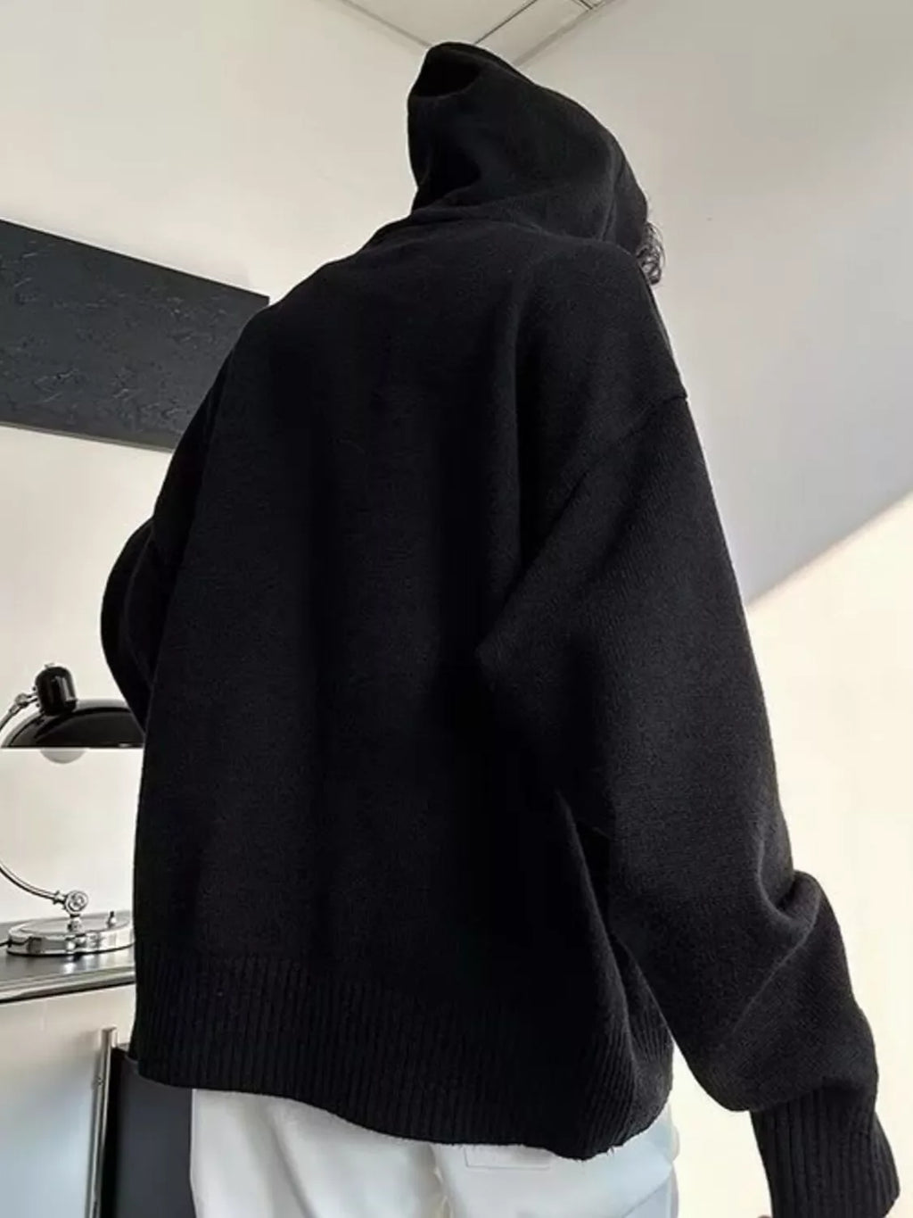 Black knit hooded sweater, side view with ribbed hem