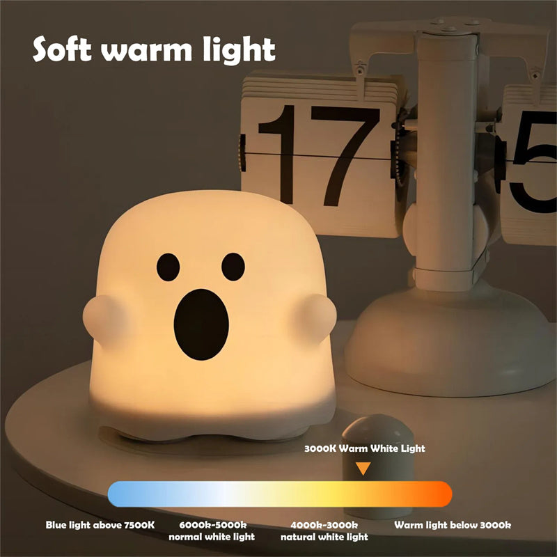 Silicone ghost night light lamp emitting soft warm white light from round base.