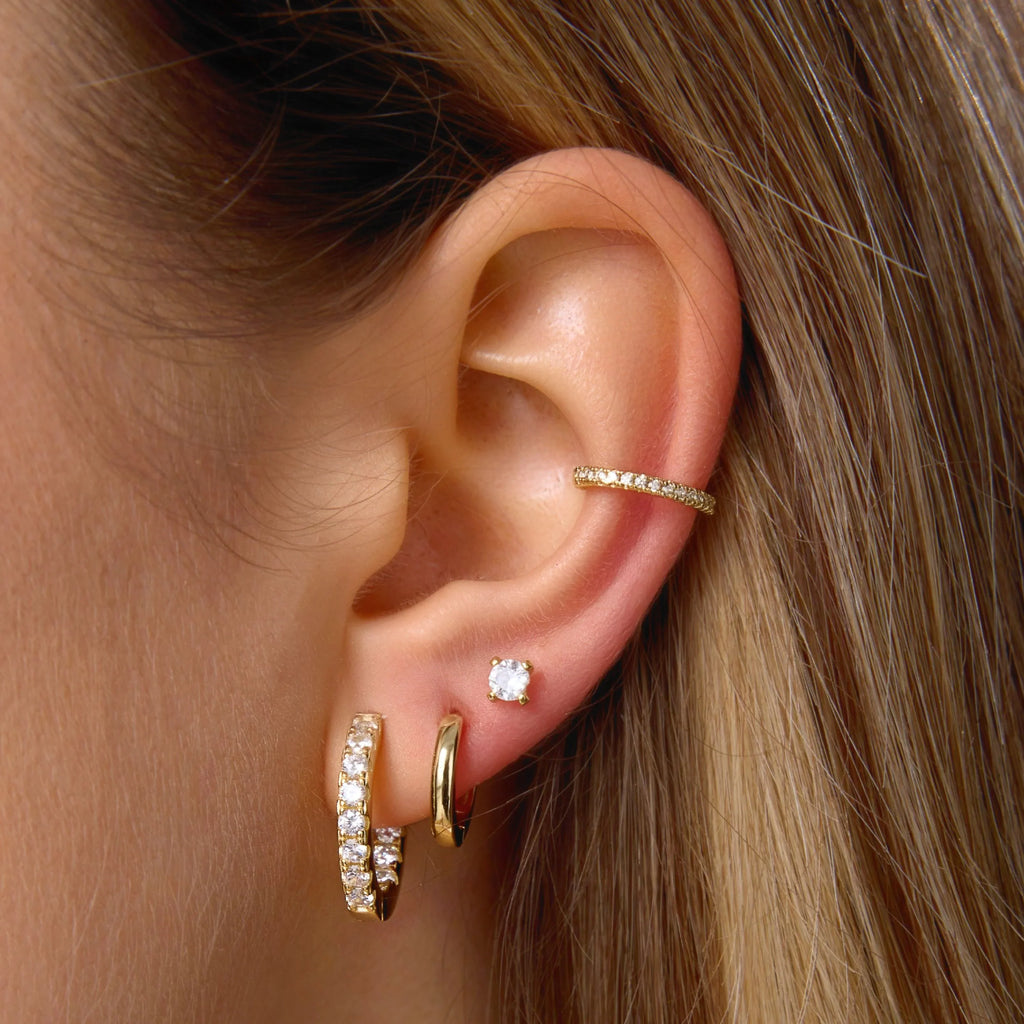 Gold-tone CZ hoop and stud earrings with pear-shaped drop charm, side view