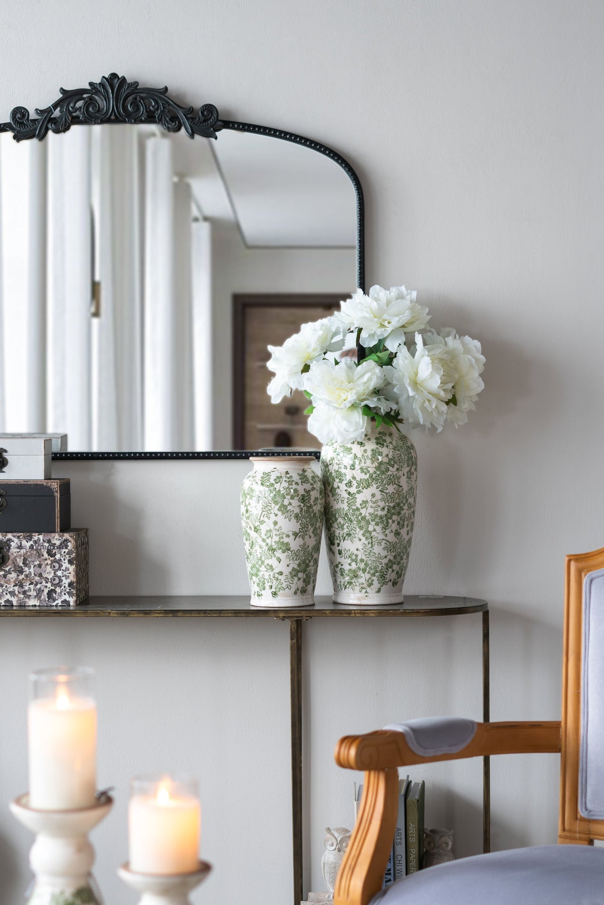White ceramic vase with green floral pattern holding white flowers