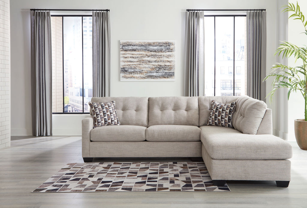 Light gray corner chaise sectional with chaise extension, tufted cushions, and accent pillows