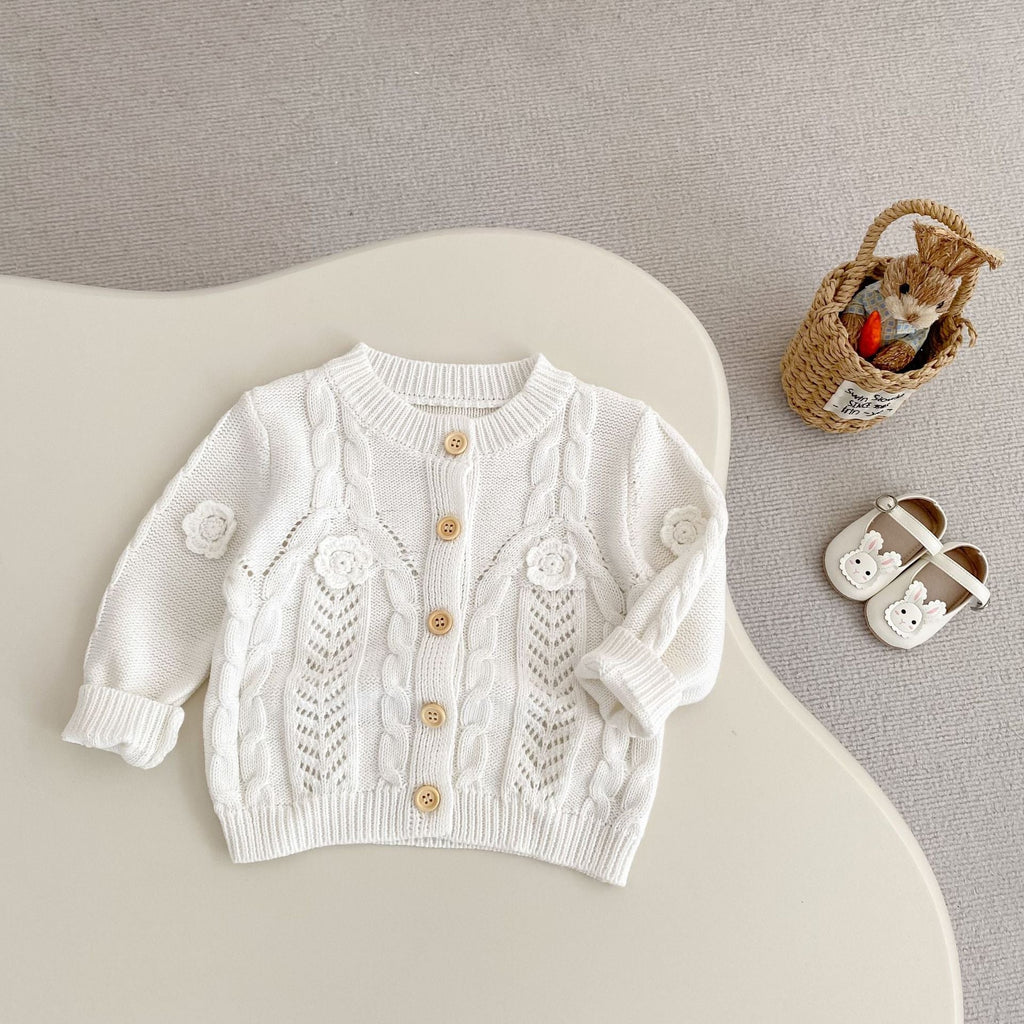 Cream baby knit cardigan with cable-knit texture, floral appliques, gold button closure