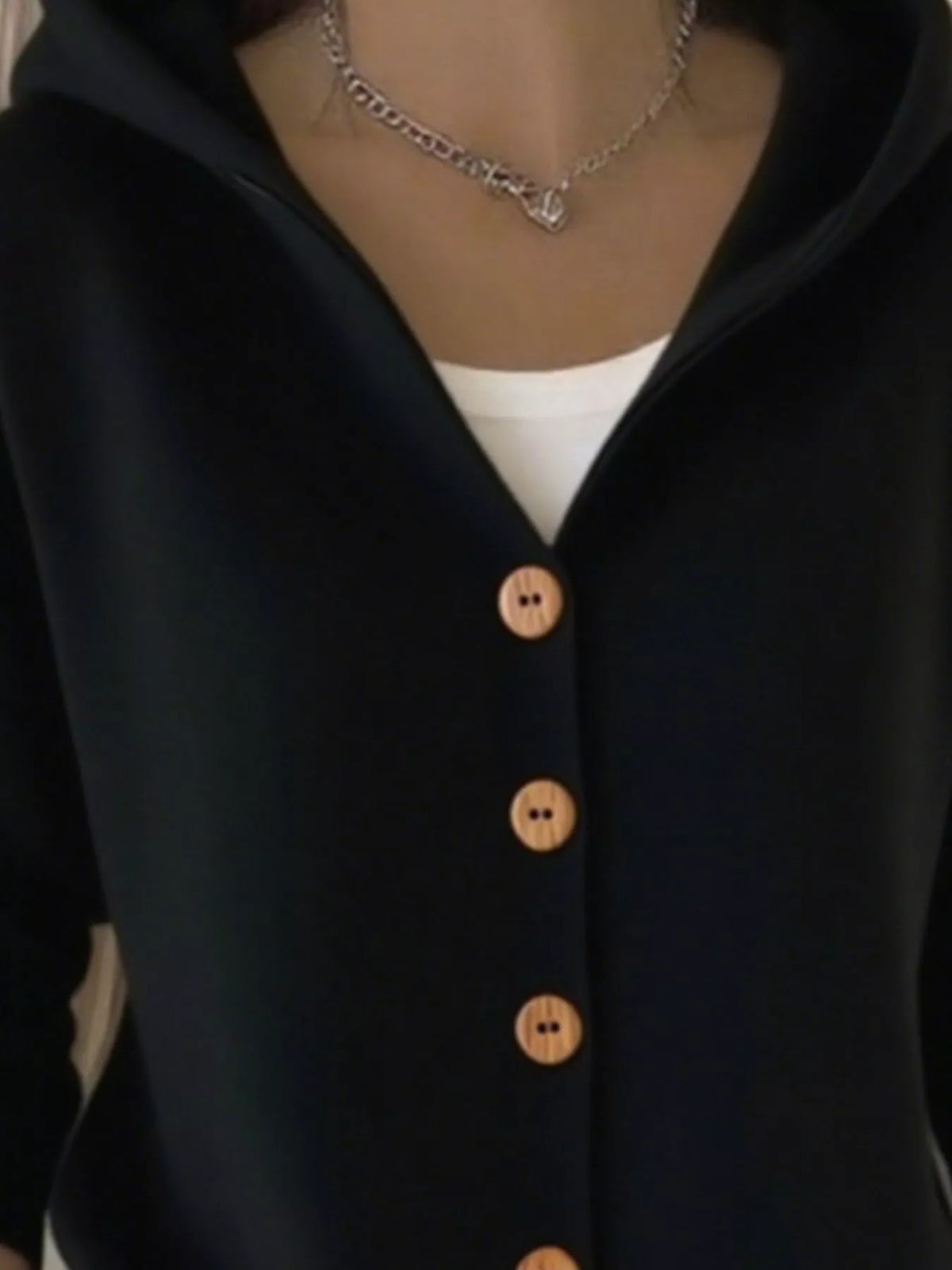 Black hooded knit cardigan close-up, wooden-style front buttons