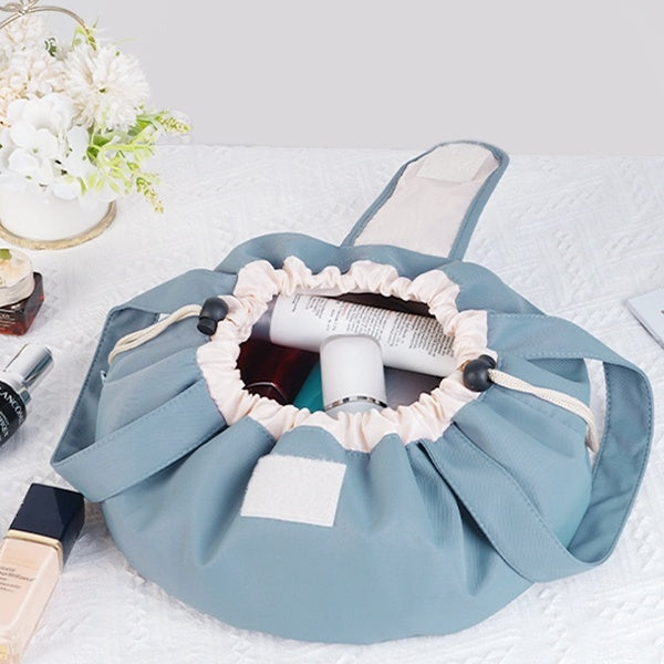 Light blue barrel drawstring makeup bag open with cream drawstring and inner items