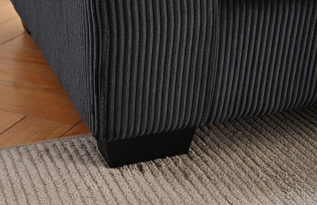 Textured dark sectional sofa corner with thick seat and low, squared arms